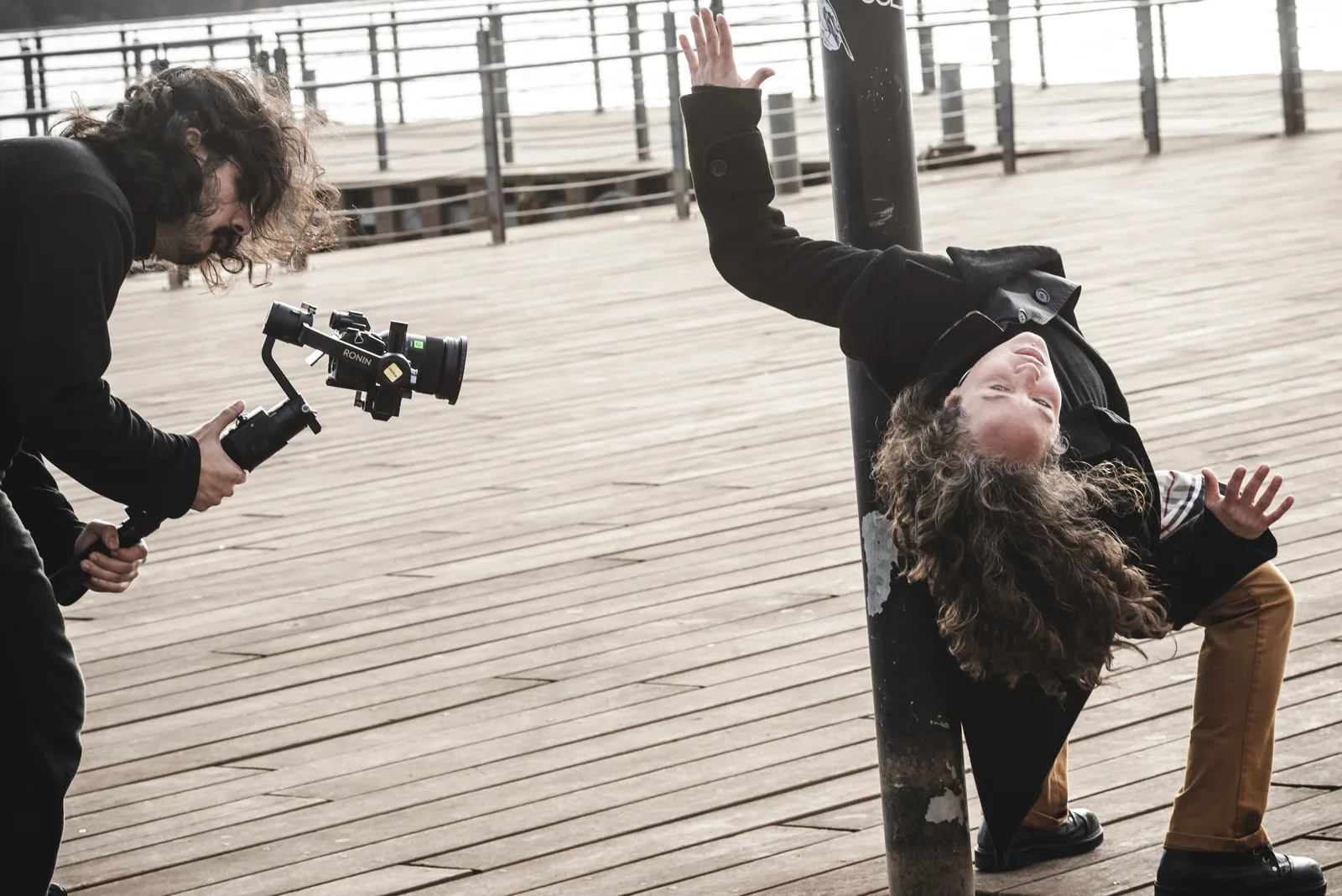 Gimbal camera filming a dancer leaning against a post on a wooden pier
