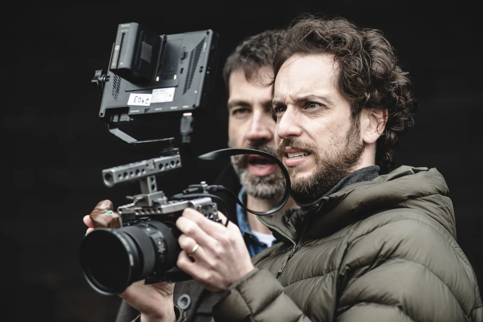 Caio Amon operating a camera with an external monitor, beside another crew member